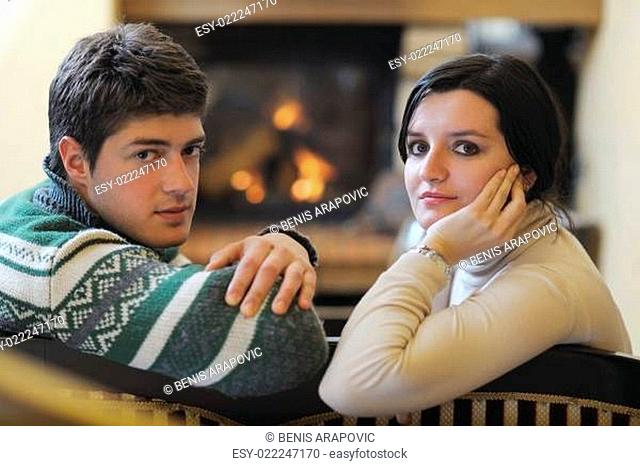 Young romantic couple sitting and relaxing in front of fireplace