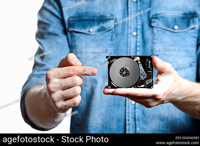 Man's hand holds a 2.5 inch hard drive. He's points to the hard disk. View of the backside HDD, from the PCB. Isolated on white background