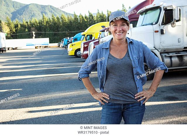 A Caucasian woman truck driver near her truck parked in a parking lot of a truck stop