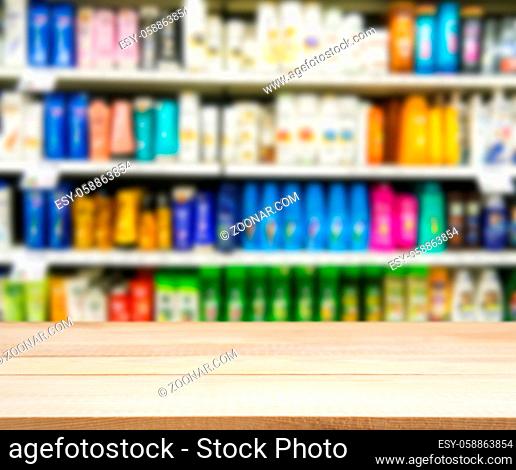 Wooden board empty table in front of blurred background. Perspective light wood board over blurred colorful supermarket products on shelvest - mock up for...