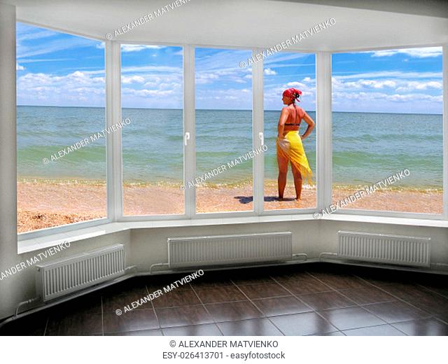 window with view to the sea and girl in pareo sunburnting at the seacoast