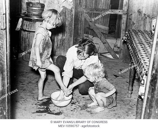 Mother washing feet and cleaning up daughters in sharecropper's shack. Southeast Missouri Farms. Date 1938 May