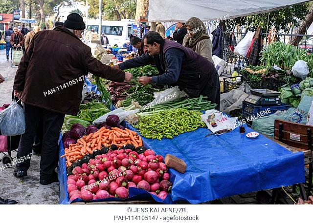 11.12.2018, Turkey, Tire: Market day in Tire in the turkish province Izmir. A man buys fresh vegetables at a market stall at a handler