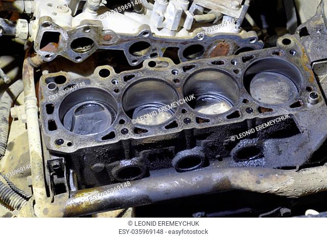 The cylinder block of the four-cylinder engine. Disassembled motor vehicle for repair. Parts in engine oil. Car engine repair in the service