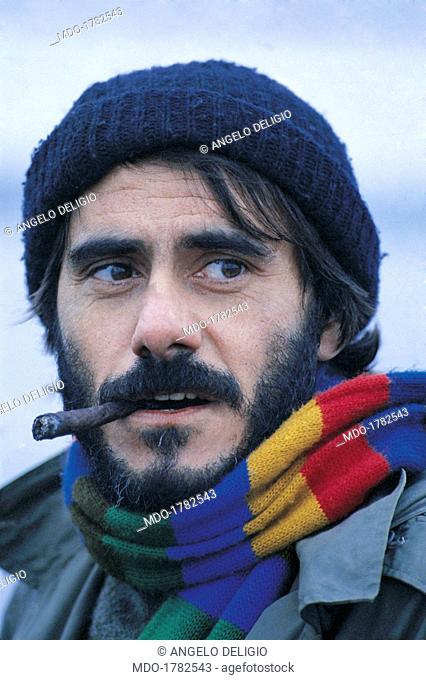 Roberto Vecchioni smoking the cigar. Italian singer-songwriter and writer Roberto Vecchioni with a cigar in his mouth wearing a wool hat and a multicolour scarf