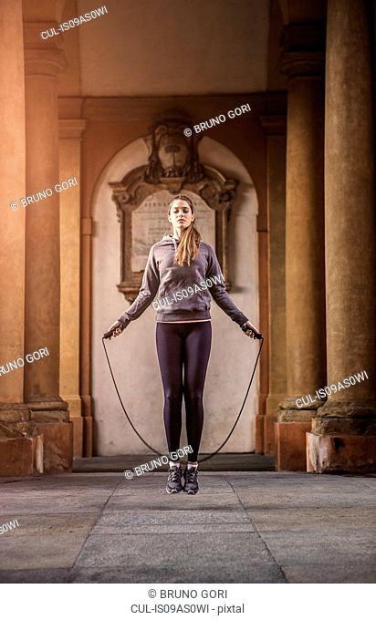 Front view of woman wearing sports clothes using skipping rope