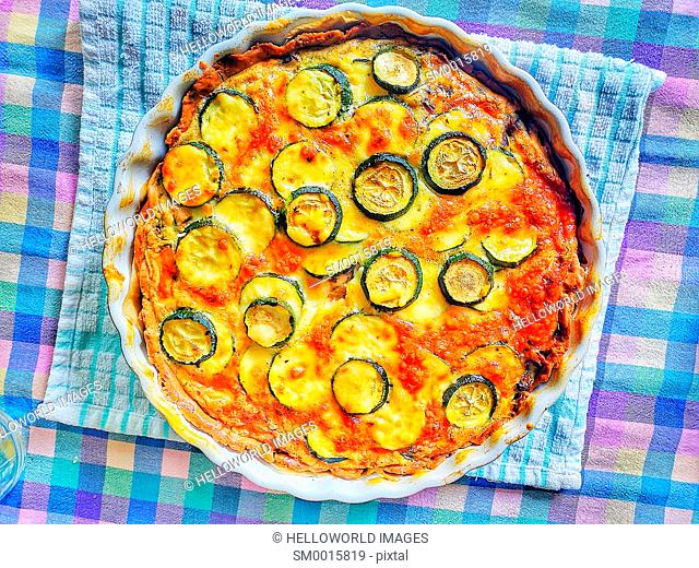 High angle shot of homemade courgette quiche on checked tablecloth