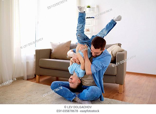 family, childhood, fatherhood, leisure and people concept - happy father and little son playing and having fun on sofa at home