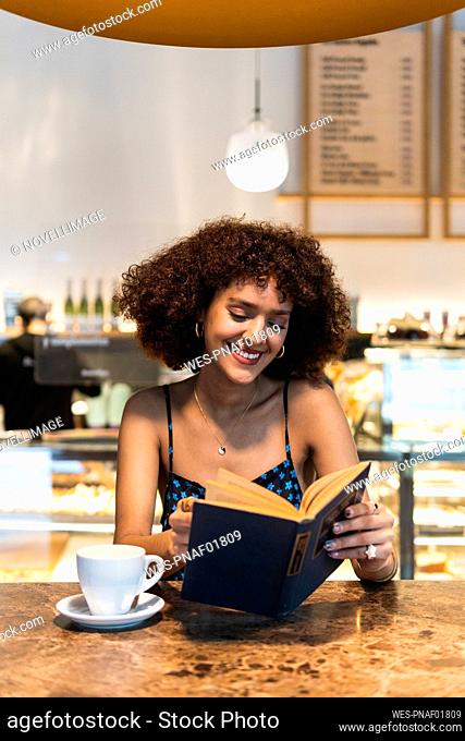 Smiling woman reading book at coffee shop