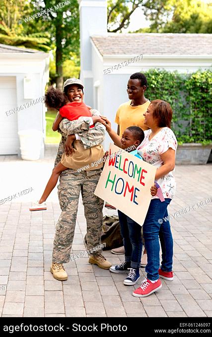 Happy female mid adult african american soldier embracing daughter while family welcoming her