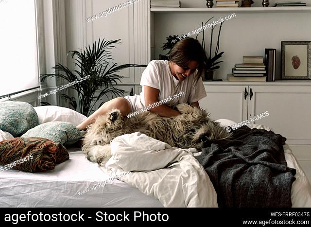 Mature woman cuddling her dog on bed