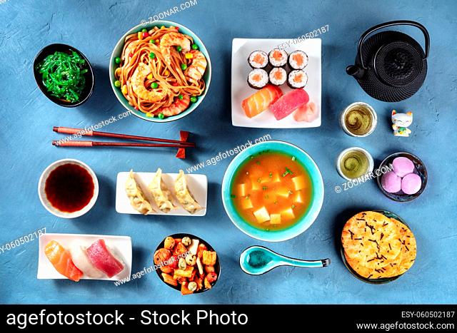 Japanese Food, Sushi, udon, miso soup, tea, mochi etc, overhead flat lay shot on a blue background