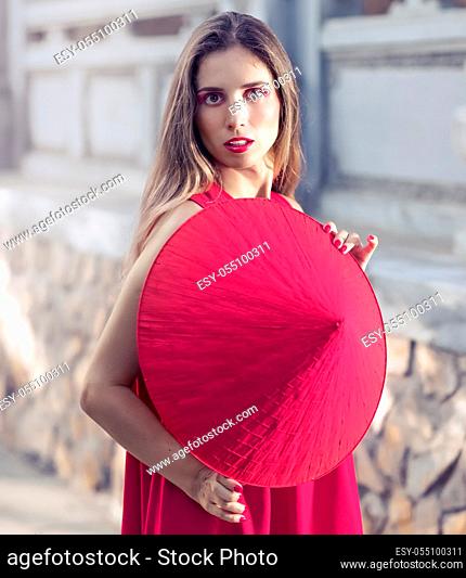 Fashion portrait of a beautiful woman in red conical hat outdoor