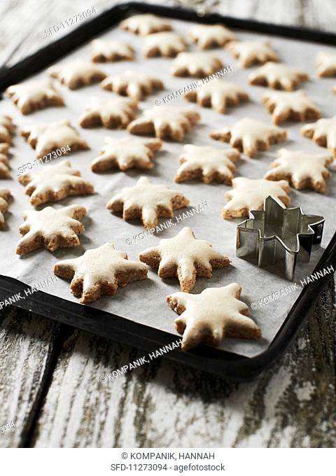Cinnamon stars on a baking tray with a cutter