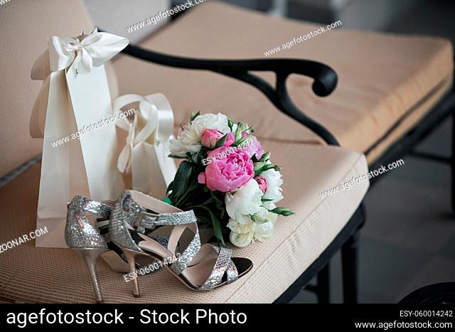 Wedding. Bouquet of pink, white flowers and greenery is in a chair against next to the bride's shoes