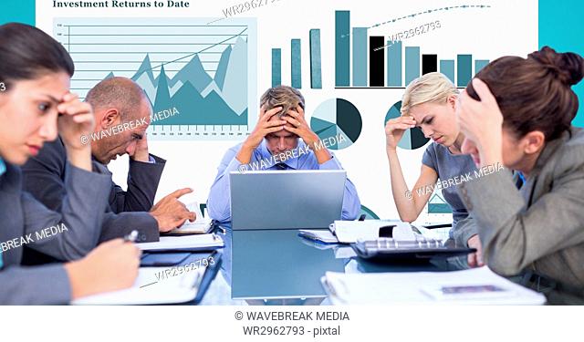 Tensed business people with head in hands against graphs