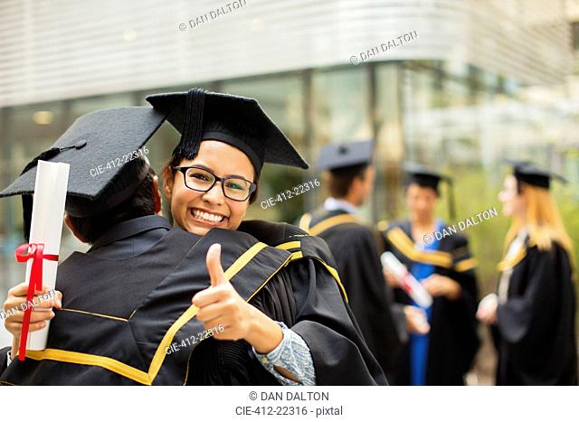 Students in cap and gown hugging