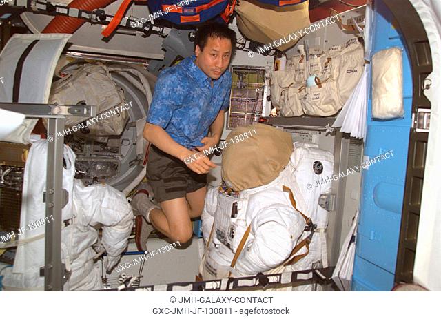 Astronaut Edward T. Lu, Expedition 7 NASA ISS science officer and flight engineer, floats near the torso portions of the Extravehicular Mobility Unit (EMU)...