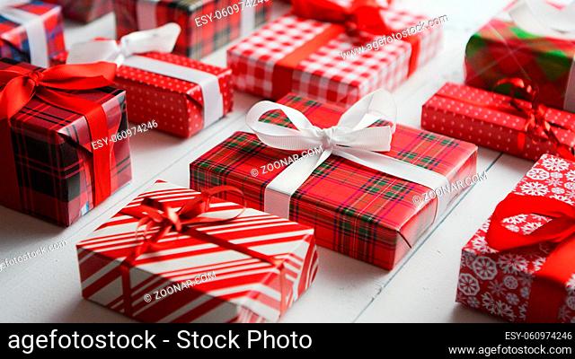 Side view of wrapped Christmas presents laid on the white wooden table