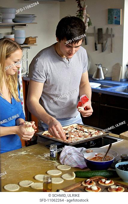 A young woman and the young man making pizza