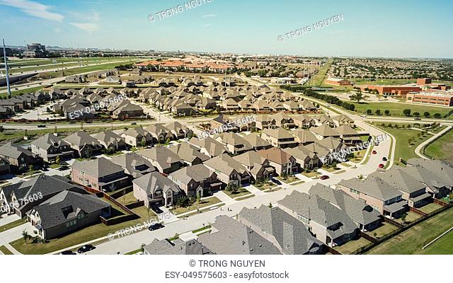 Aerial view new residential neighborhood situated between highway and school district near Dallas, Texas, USA. Row of single-family houses with gardens