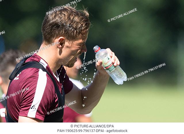 25 June 2019, Saxony, Dresden: Dynamos Jannik Müller tilts water from a bottle over his head during training. Photo: Sebastian Kahnert/dpa-Zentralbild/ZB