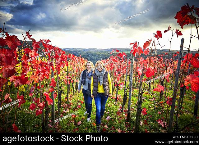 Two mature woman strolling through a vineyard