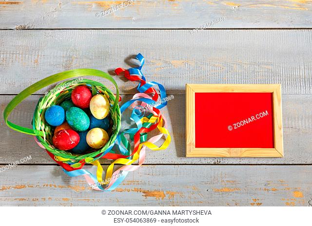 Easter eggs in a basket with colored ribbons, frame with copy space