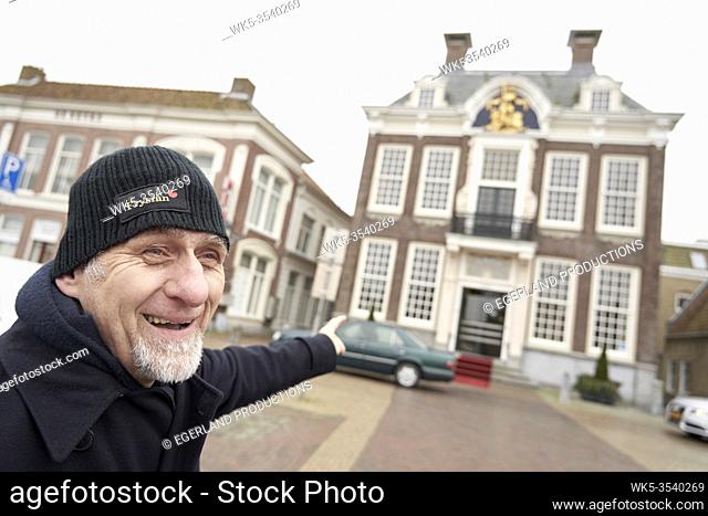 Friesian senior man pointing finger at city hall of Harlingen, Friesland, Netherlands