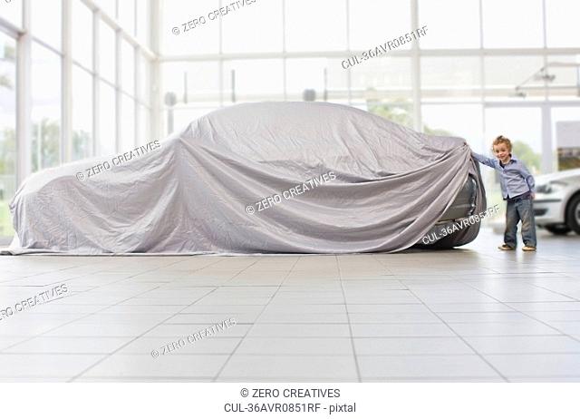 Girl peeking under cloth on car