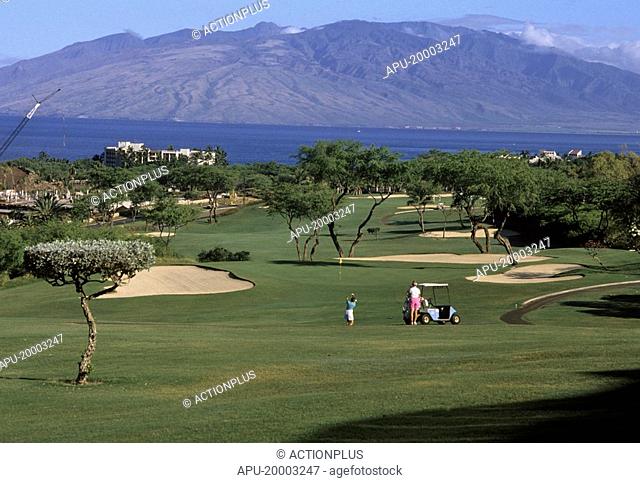 Golfers on a golf course by a lake