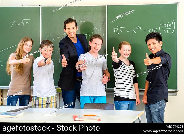 School and education - Teacher and students stand in front of a blackboard with math work in a classroom or class