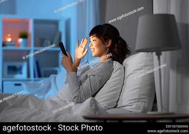woman with phone having video call in bed at night