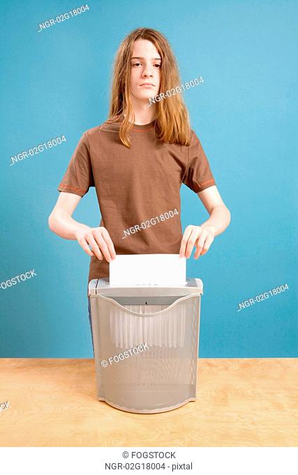 Teen Boy in Act of Shredding Blank Paper