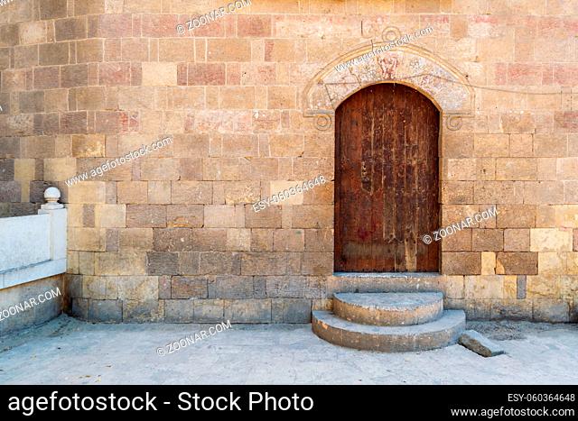 External vaulted grunge closed wooden door in bricks stone wall, public historic Amir Aqsunqur Mosque, Blue Mosque, Cairo, Egypt