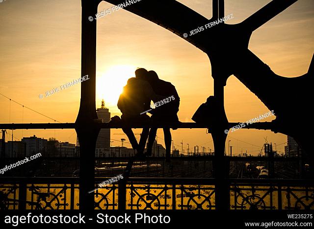 Munich, Germany, March 23, 2017: A couple watches the sunset from a bridge over the railroad tracks