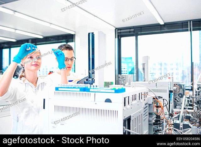 Two young researchers carrying out scientific research in a lab using a gas chromatograph (shallow DOF; color toned image)