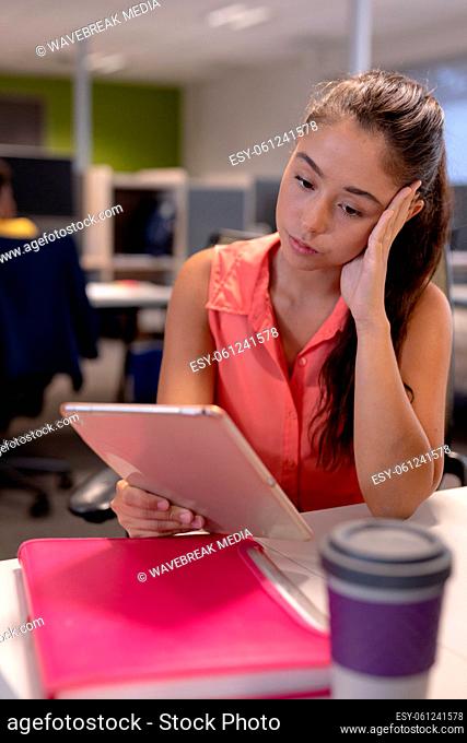Tired caucasian female advisor looking at digital tablet while working at modern workplace