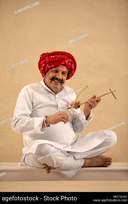 A VILLAGER HAPPILY SITTING AND PLAYING EKTARA INSTRUMENT