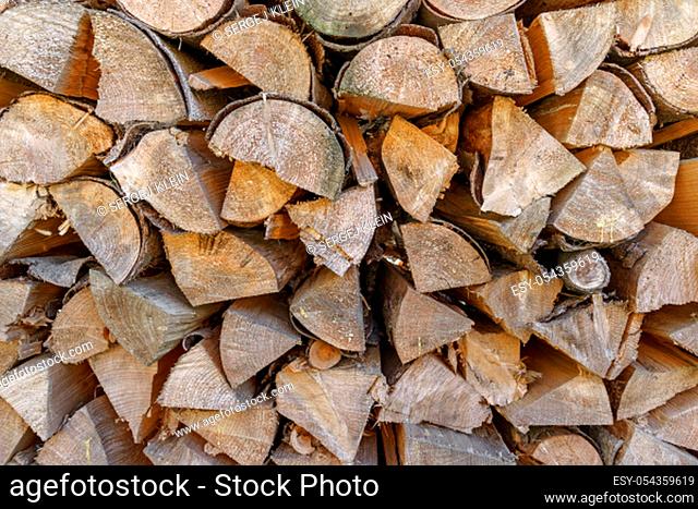 A pile of stacked firewood, prepared for heating the house. Firewood harvested for heating in winter. Chopped firewood on a stack. Wood background