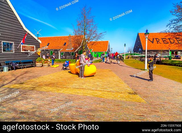 Zaanse schans, Netherlands - April 1, 2016: Large yellow wooden shoes, clogs or klompens for taking photo in Holland, people
