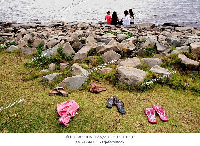 Shoes of ladies on the field and ladies sitting on a rock at the beach, miri, Sarawak, Malaysia, borneo, asia
