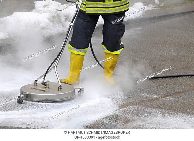 Fireman neutralising leaked brake fluid from a street with cleaning equipment