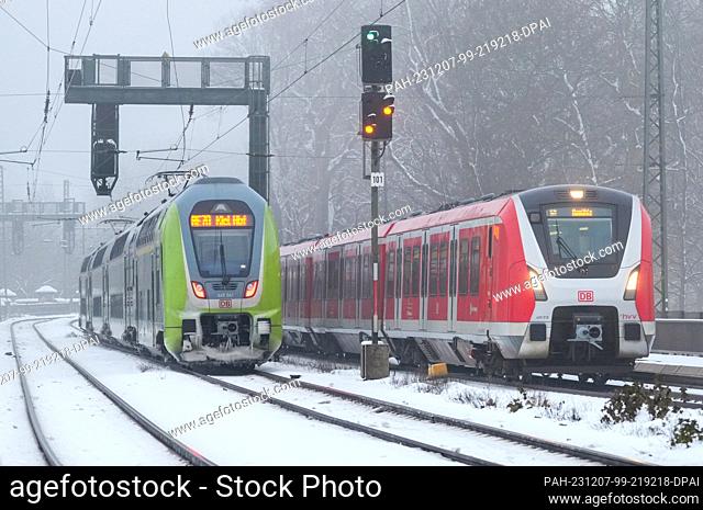 06 December 2023, Hamburg: A regional train (Regionalexpress) RE70 (l) operated by Nahverkehrsverbund Schleswig-Holstein GmbH (Nah