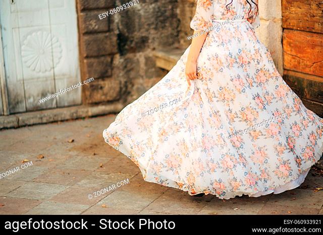 Happy beautiful bride outdoors. Wedding dress fluttering in the wind. Building in the background