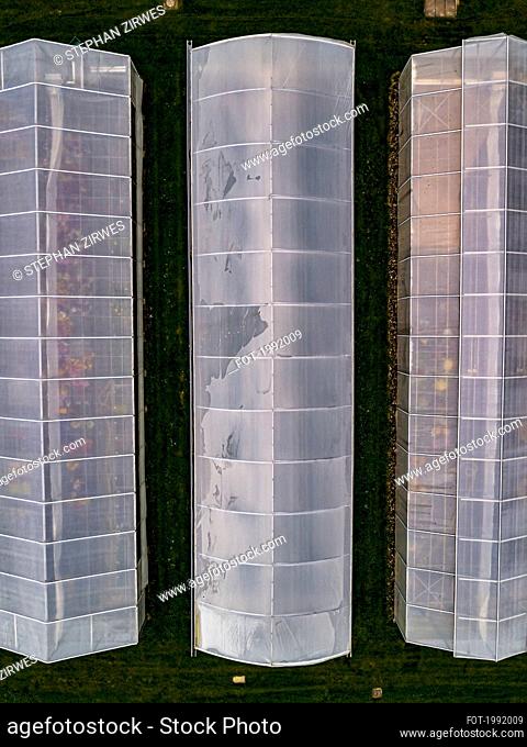 Aerial view from above sloped greenhouse roofs, Germany