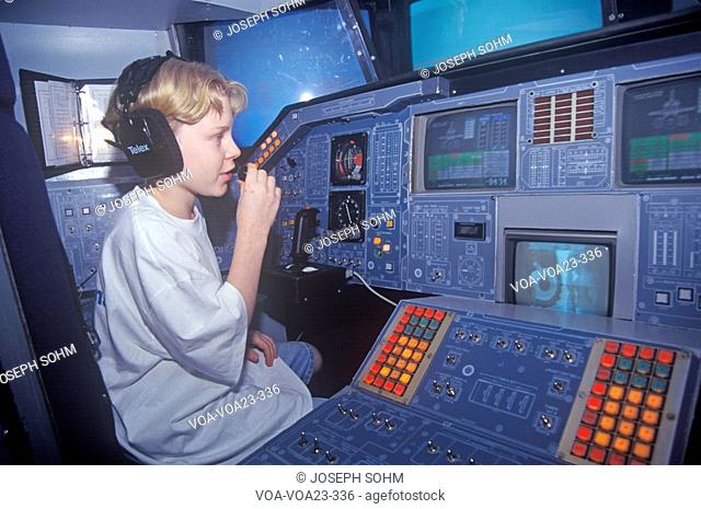 A boy attending space camp at the George C. Marshall Space Flight Center in Huntsville, Alabama, sits in the cockpit of a space shuttle flight simulator