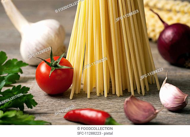 An arrangement of pasta, vegetables and parsley on a wooden table