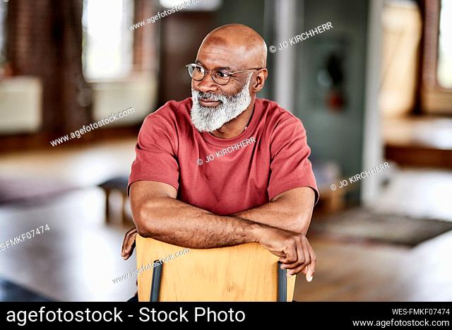 Man with eyeglasses contemplating on chair at home