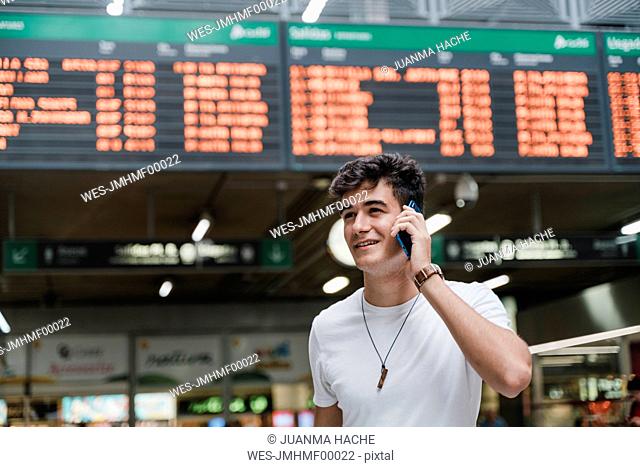 Young man waiting at train station and using smartphone